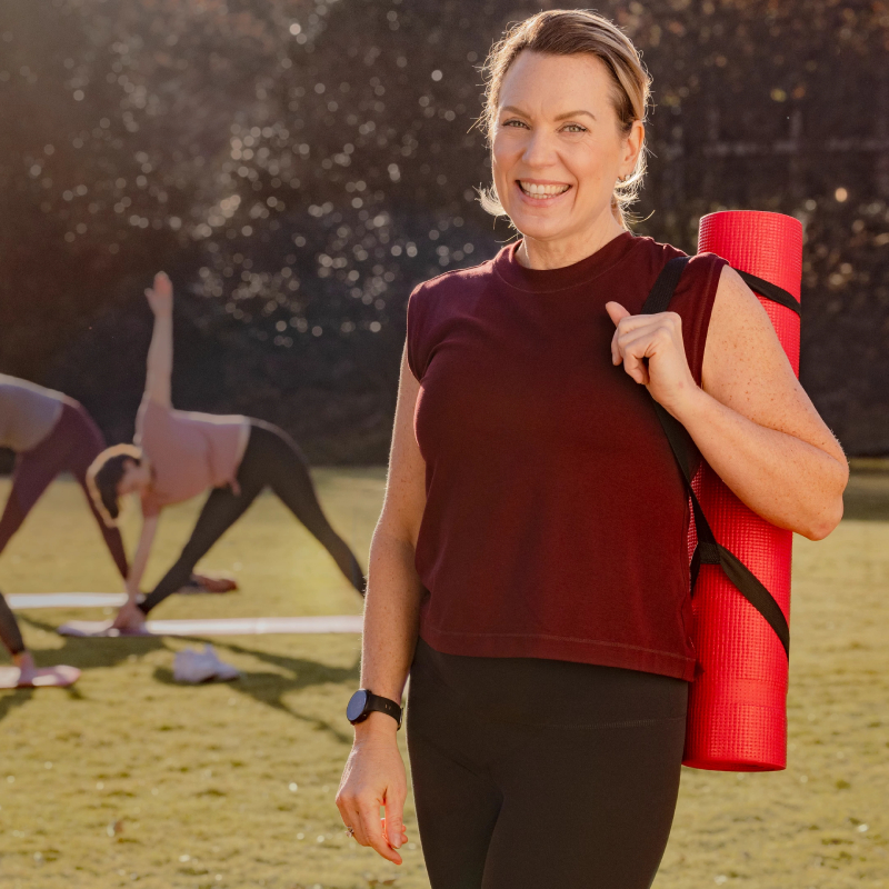 Usmievavá žena s cvičiacou podložkou cez rameno