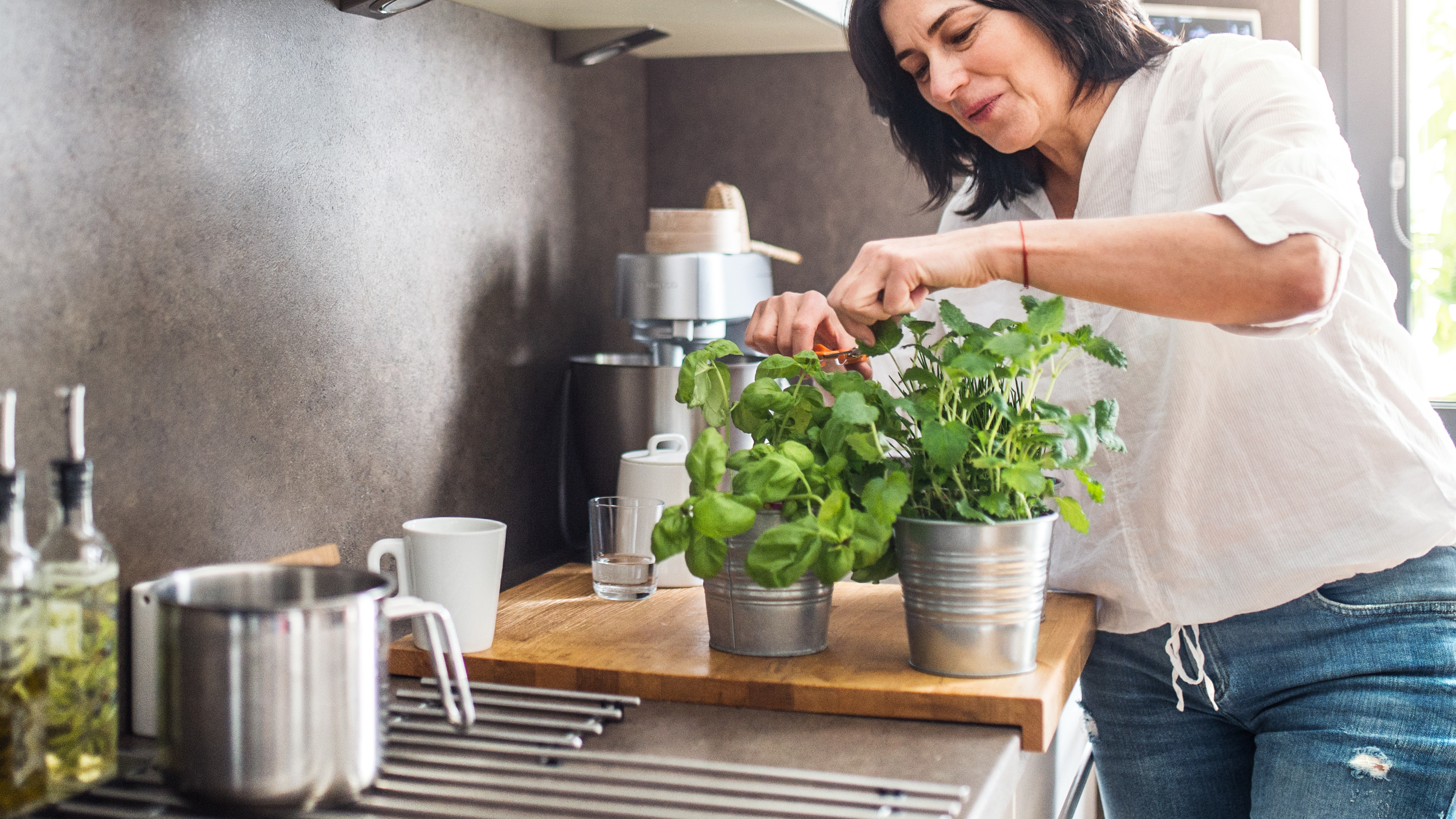 Žena strihá v kuchyni bylinky